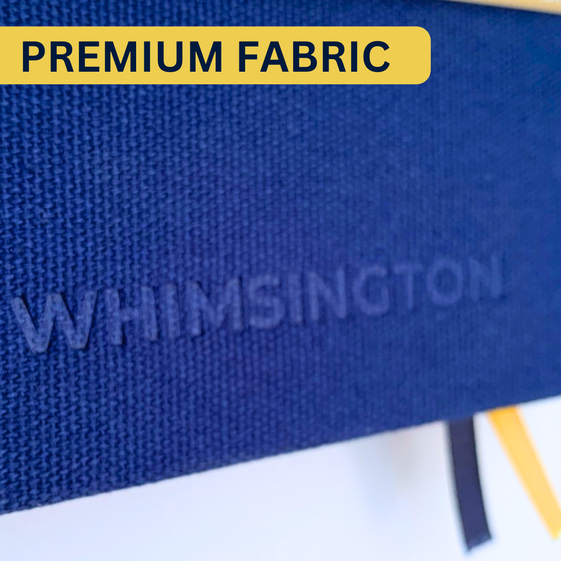 Close up of the Whimsington planner cover with the word Whimsington embossed in dark blue fabric and a label that reads Premium Fabric.