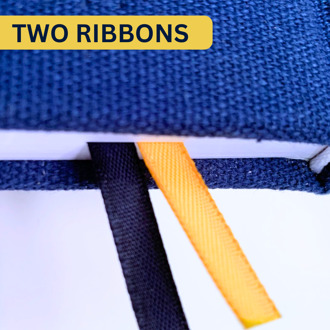 Close up of two bookmark ribbons, one navy blue and one yellow, extending from the spine of the Whimsington planner. The label says Two Ribbons.